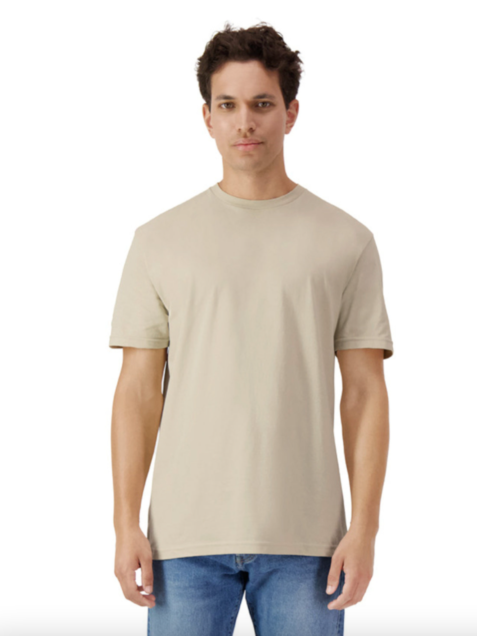 Man wearing a beige t-shirt and blue jeans on a white background